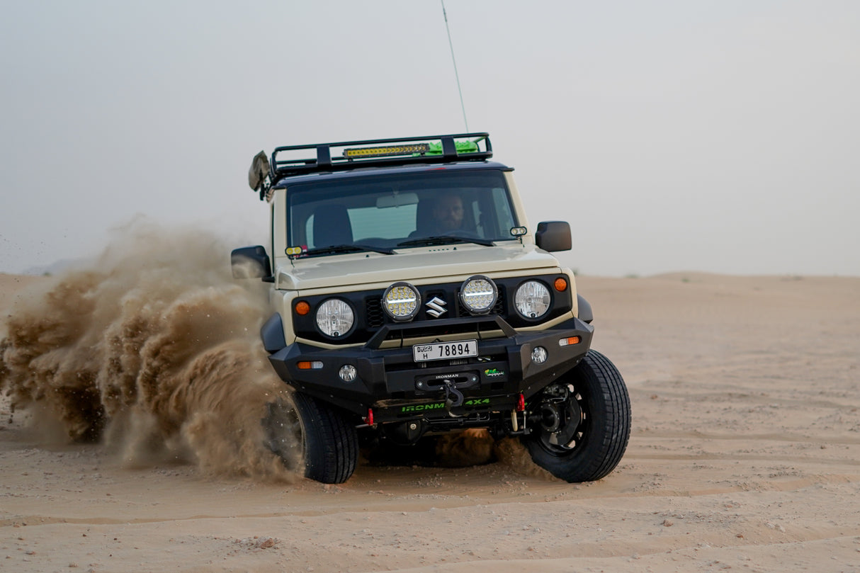 Chiffon Ivory Suzuki Jimny JB74 with Ironman 4x4 accessories driving in Dubai sand dunes