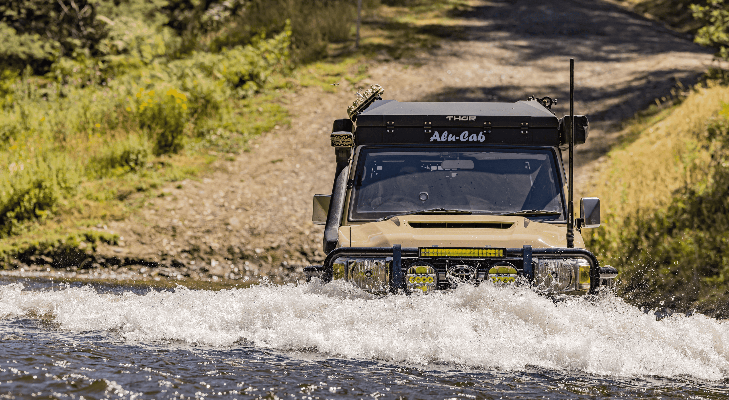 Front view of Sandy Taupe LC76 equipped with Ironman 4x4 diff breathers crossing deep river in Victorian High Country.